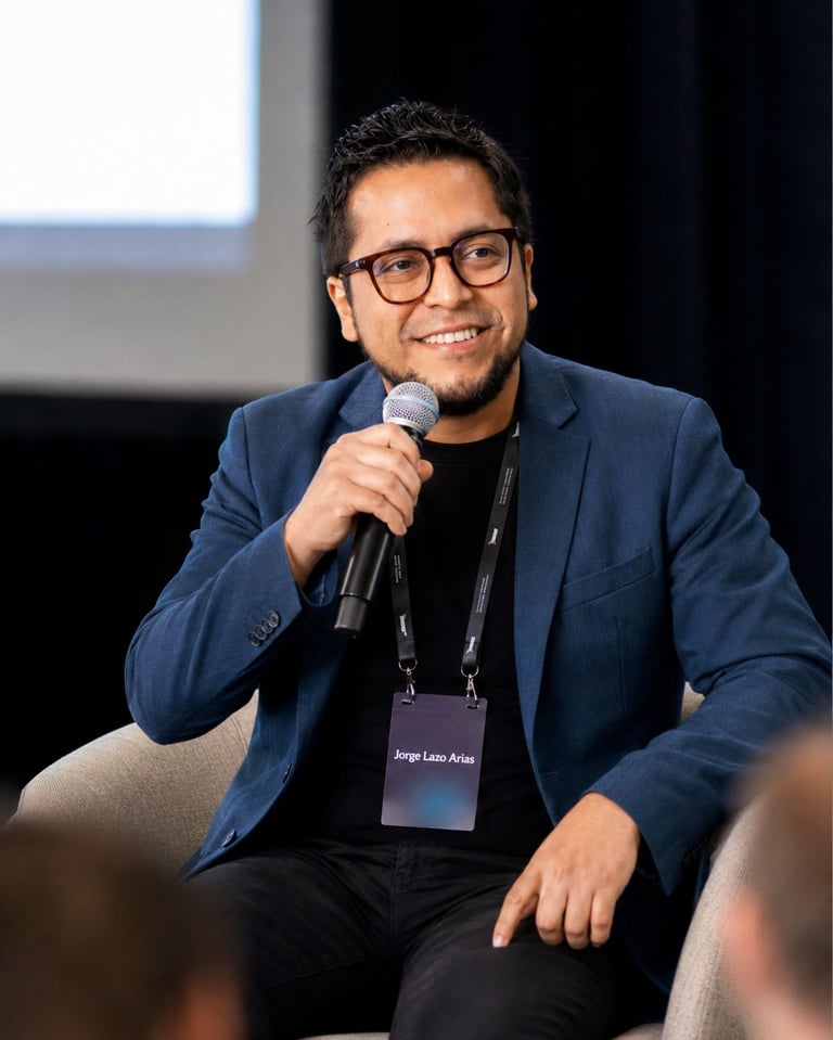 Man in blue blazer speaking at microphone wearing ID badge at event